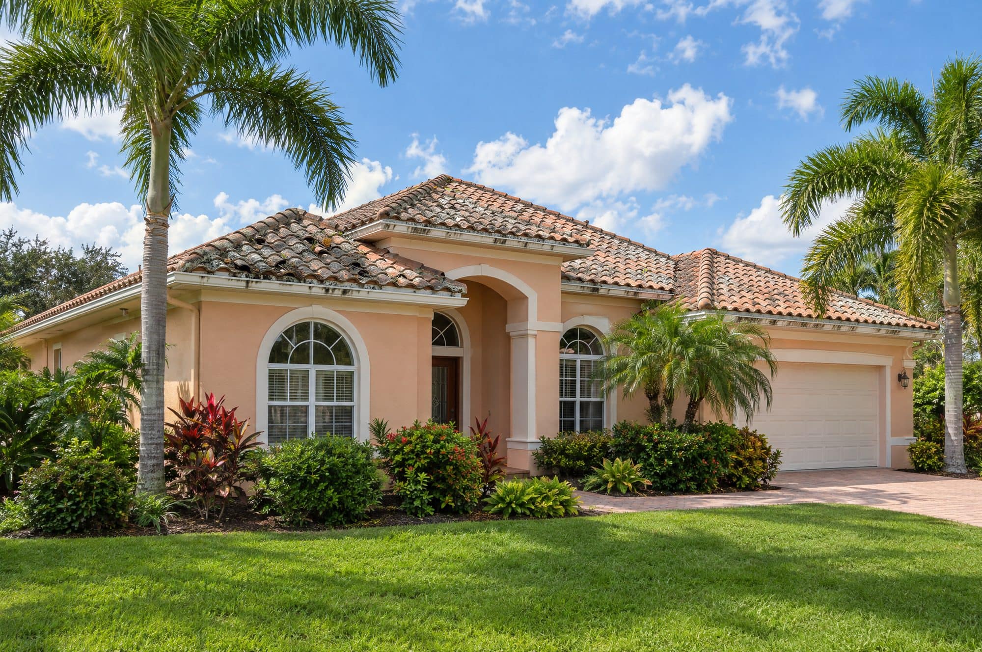 Peach stucco Spanish-style Florida home with an old tile roof darkened by mold and lichen, with cracked and slipped tiles (illustration)