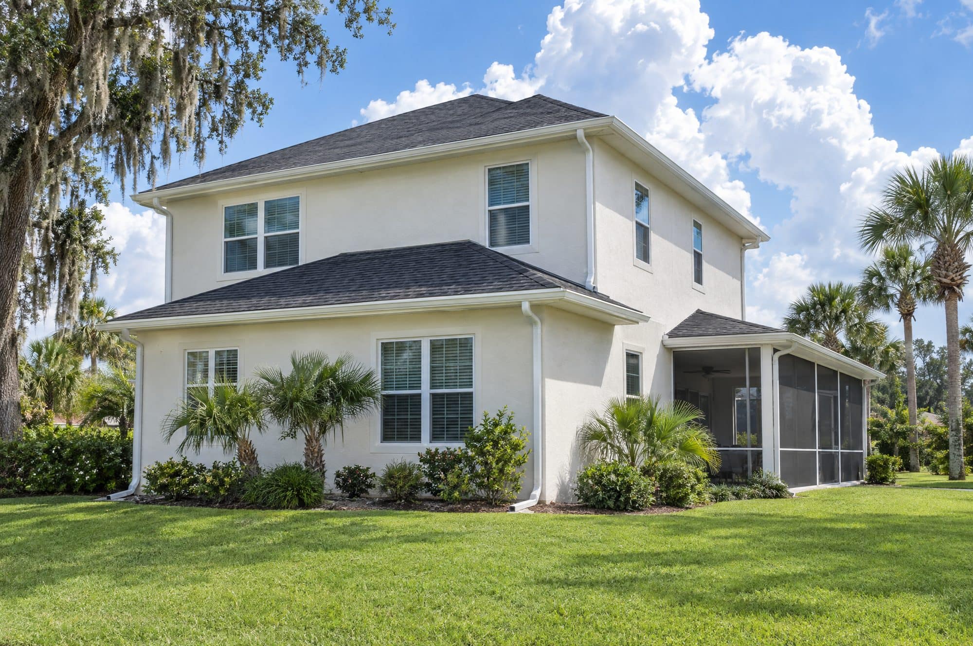 Two-story stucco house with a charcoal hip roof and white gutters and downspouts on every eave (illustration)