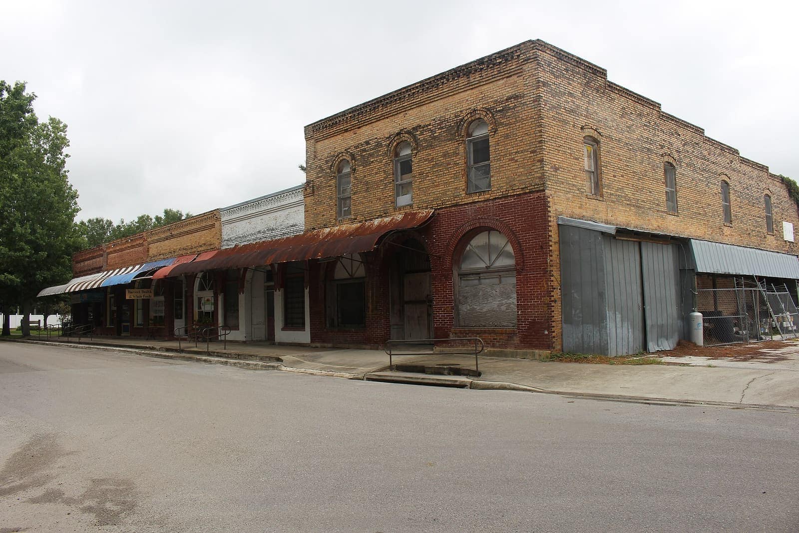 Historic brick storefronts with awnings line a quiet street under overcast skies.