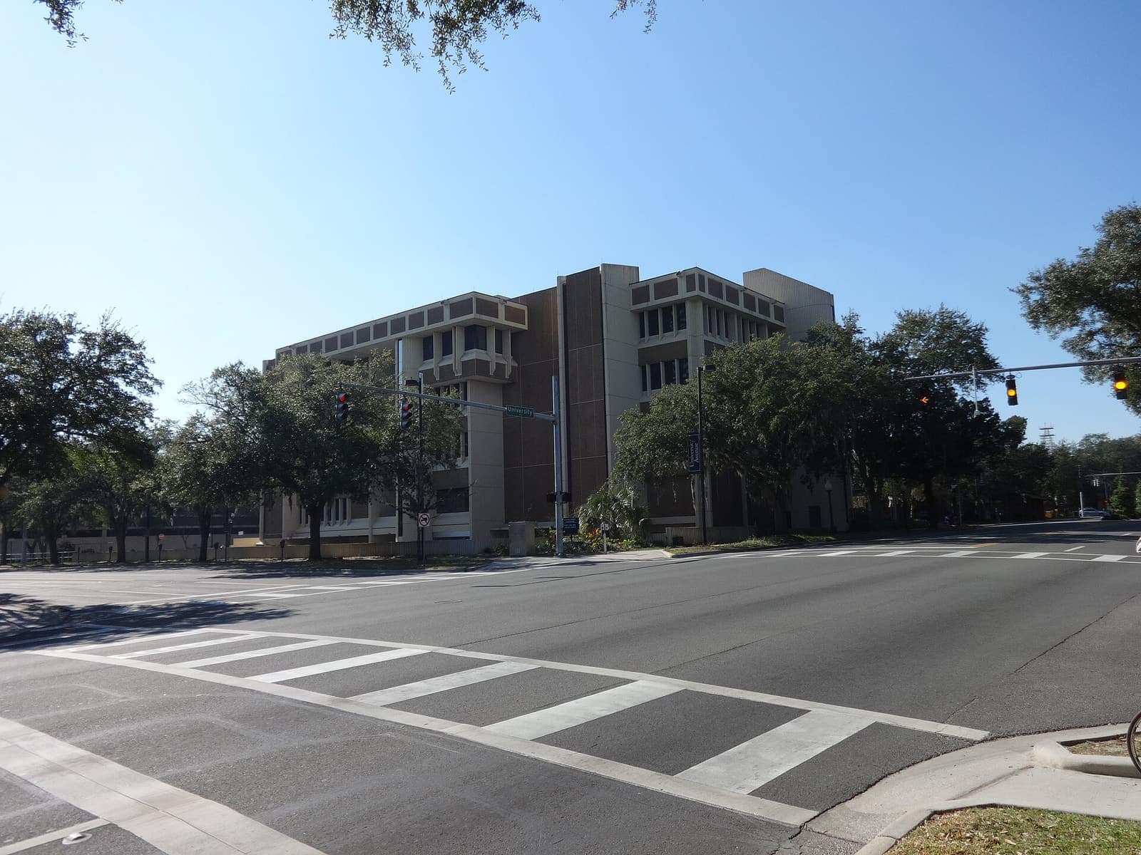 Angular modern concrete courthouse building seen across a wide intersection with trees and traffic signals.