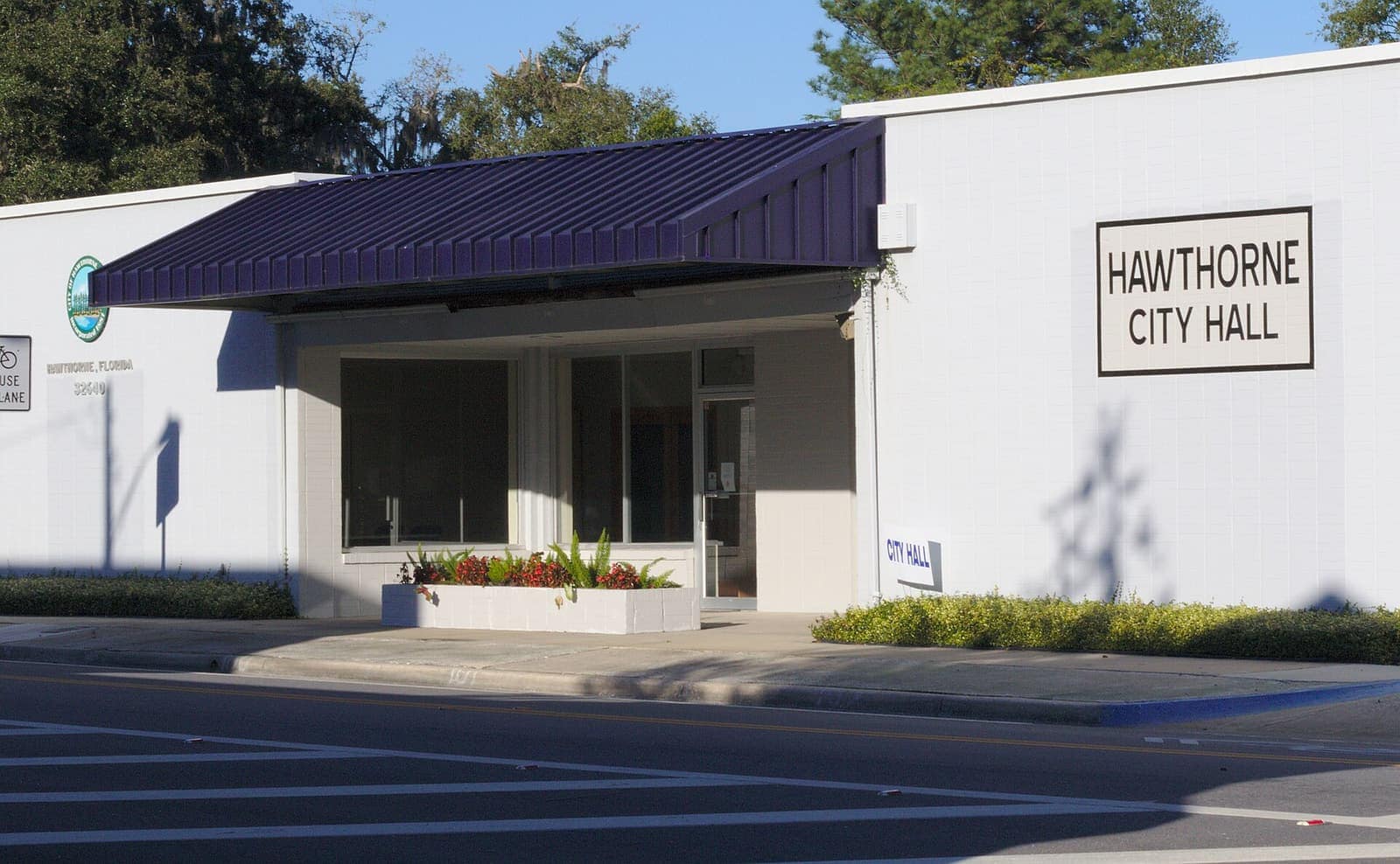 White modern city hall building with a purple metal awning and a sign reading Hawthorne City Hall.