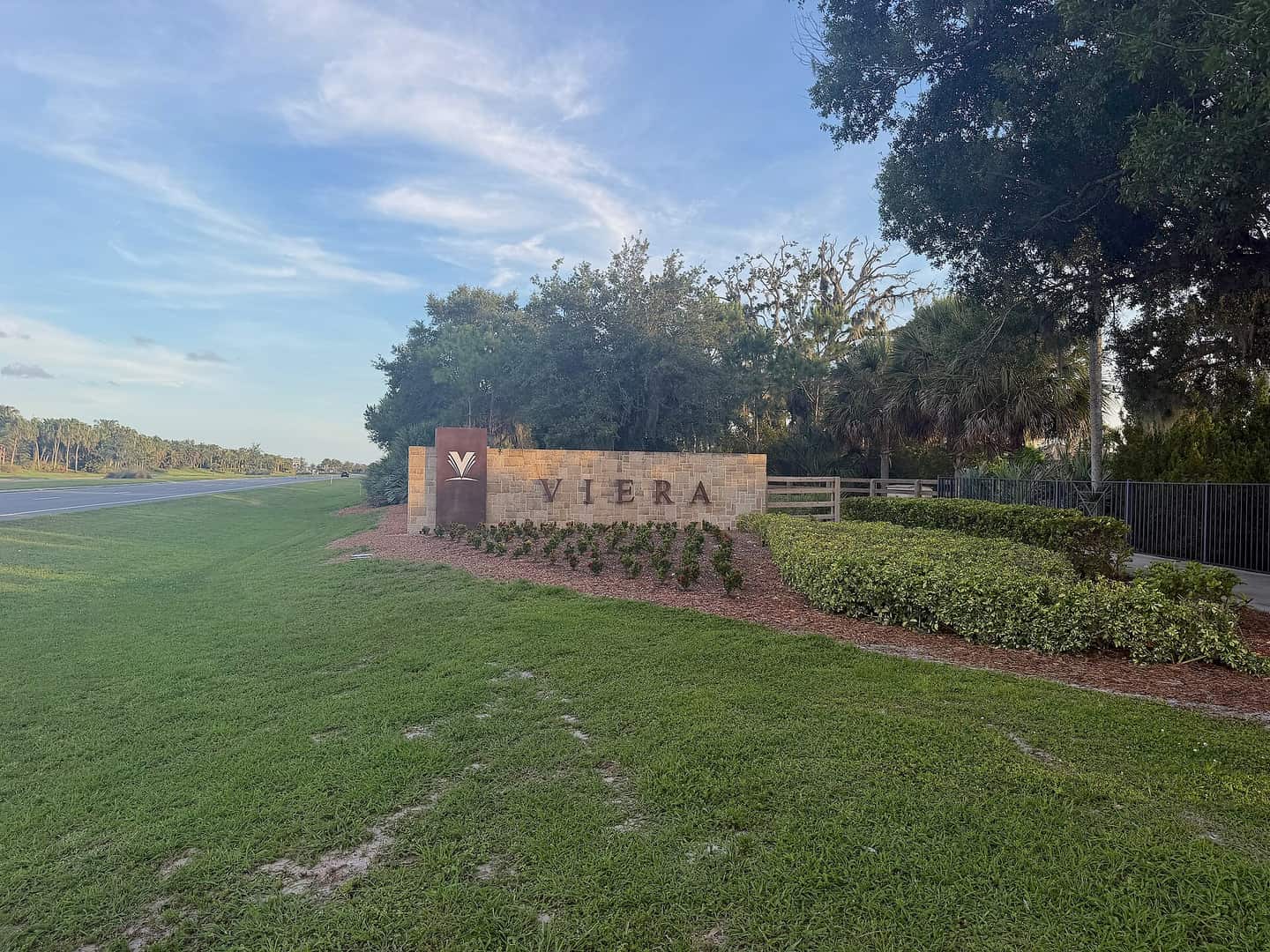 Stone entrance sign reading Viera beside a grassy lawn and road under a blue sky.