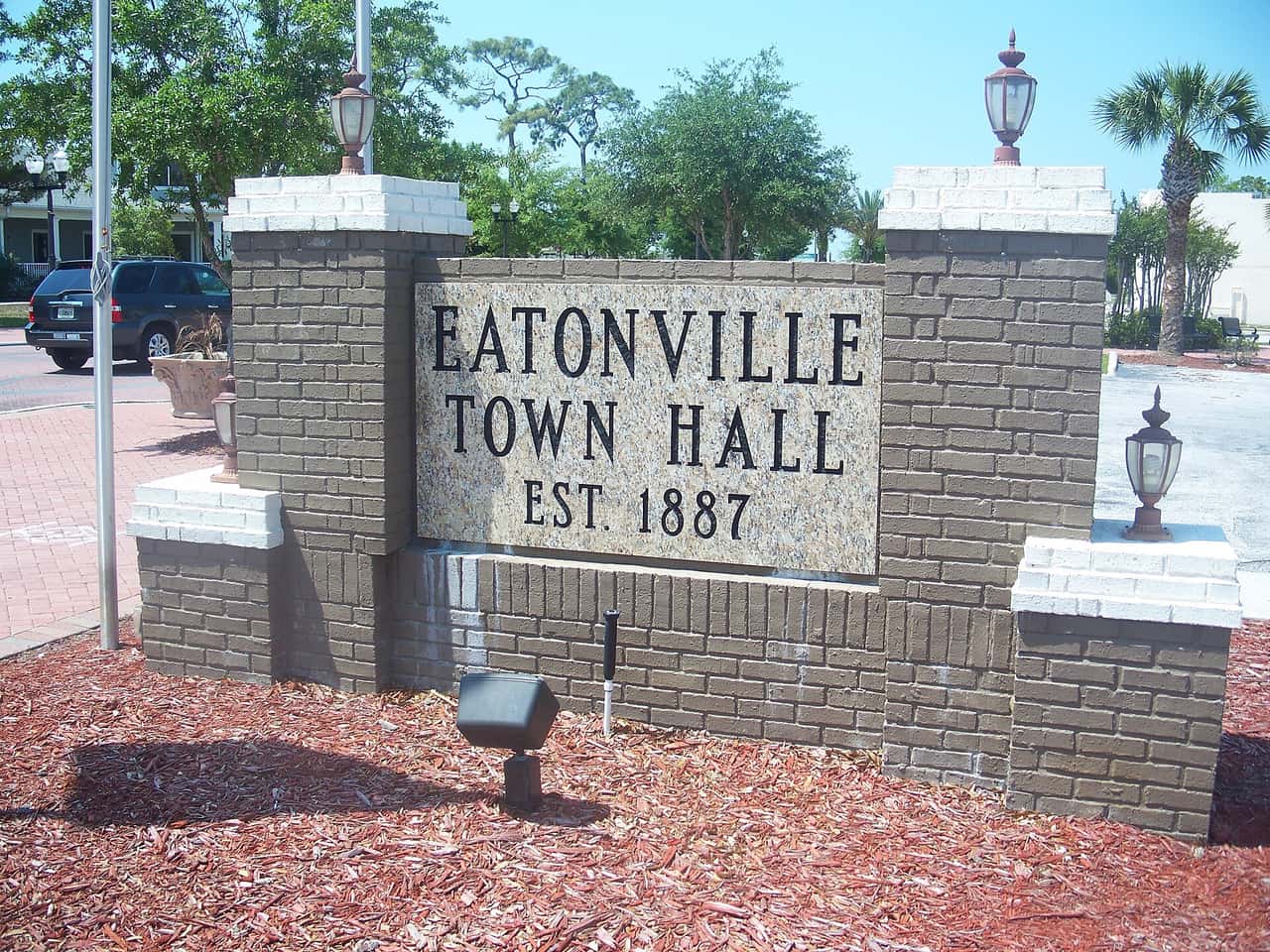Brick entrance monument sign reading Eatonville Town Hall, Est. 1887, with lamps and mulch beds.