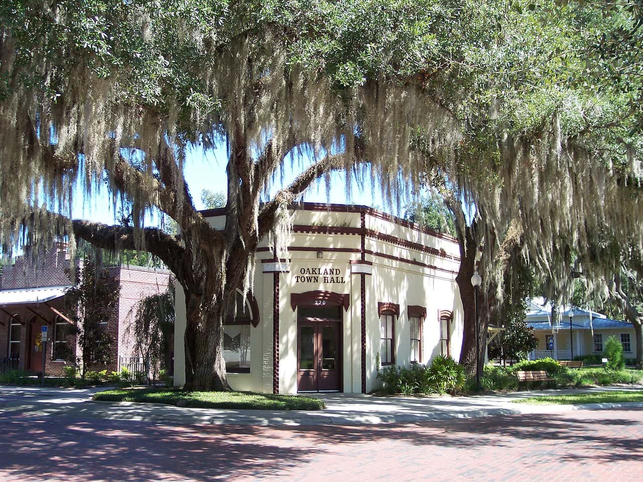 Cream stucco town hall with Spanish moss draped oaks and a brick walkway.