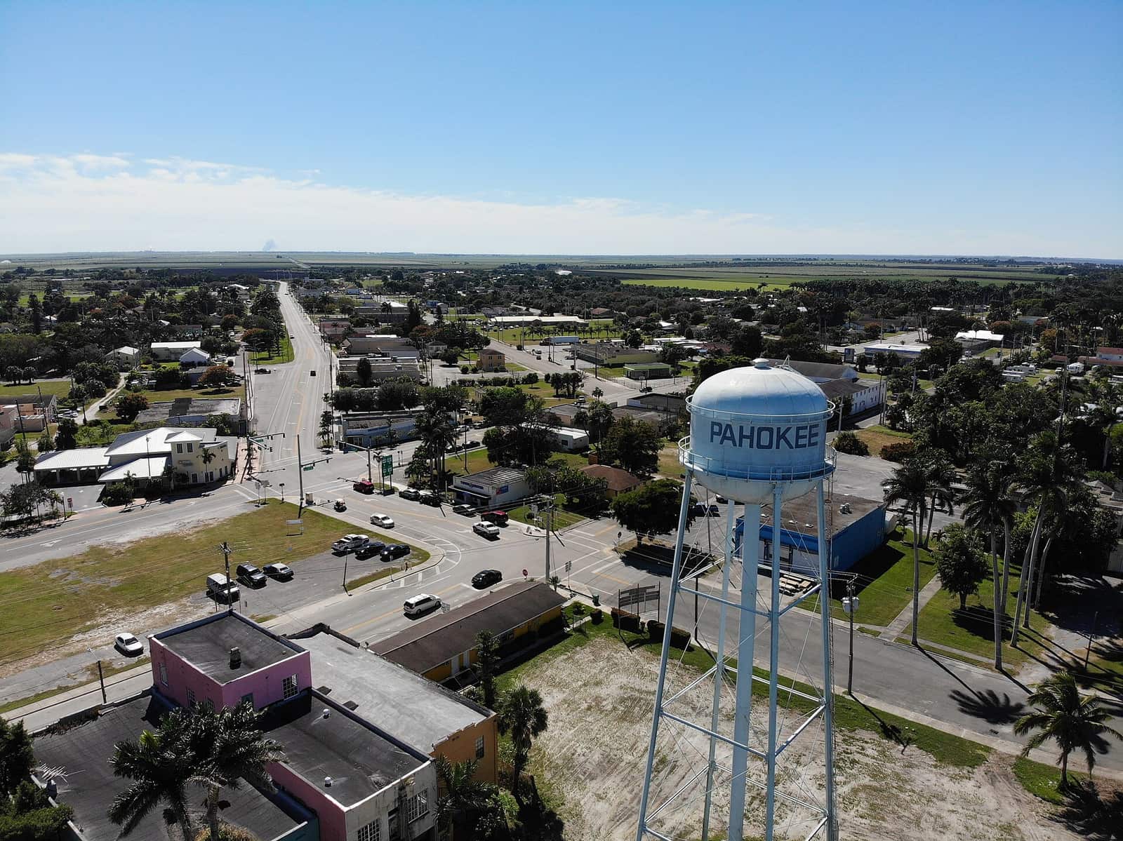 Aerial view of a white water tower labeled Pahokee above a small town street grid and palm trees.